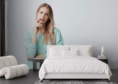 Indignant blonde female student being dissatisfied with results of exam or competition, can`t believe she made mistakes. Tired woman listens in displeasure lecture, keeps finger on opened mouth Wall mural